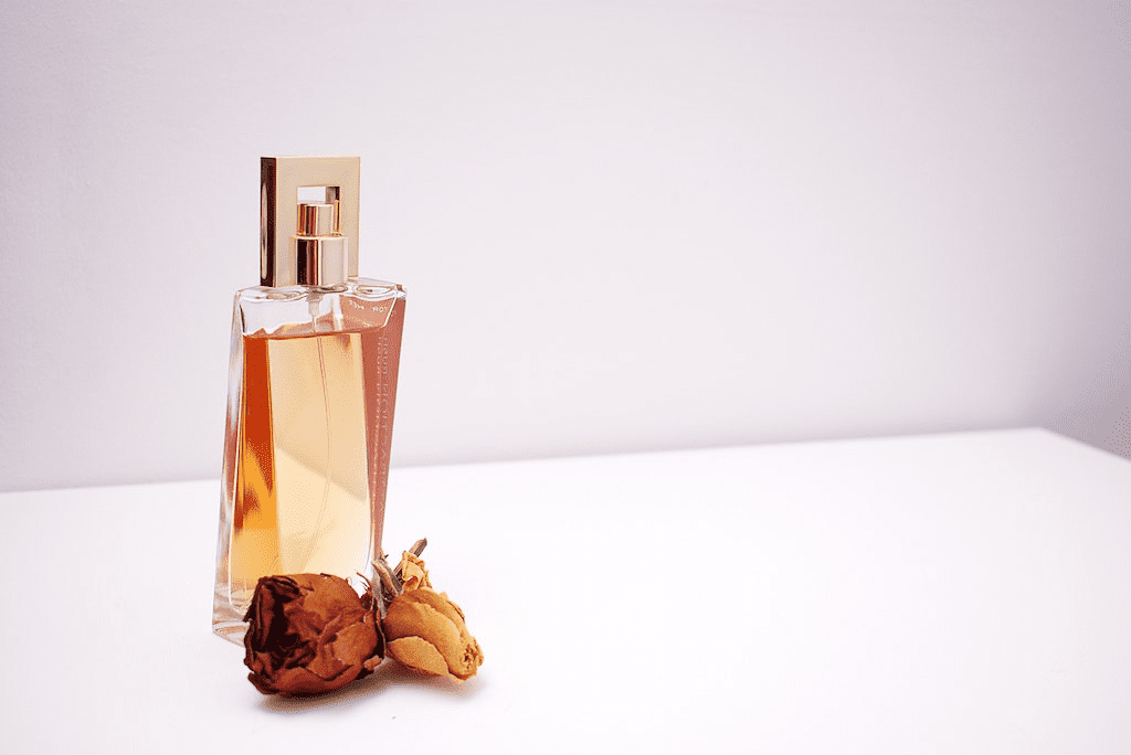 Frasco de vidro com perfume e flor seca simbolizando notas olfativas.