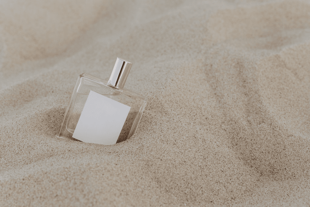 Close-up de um frasco de perfume na areia.
