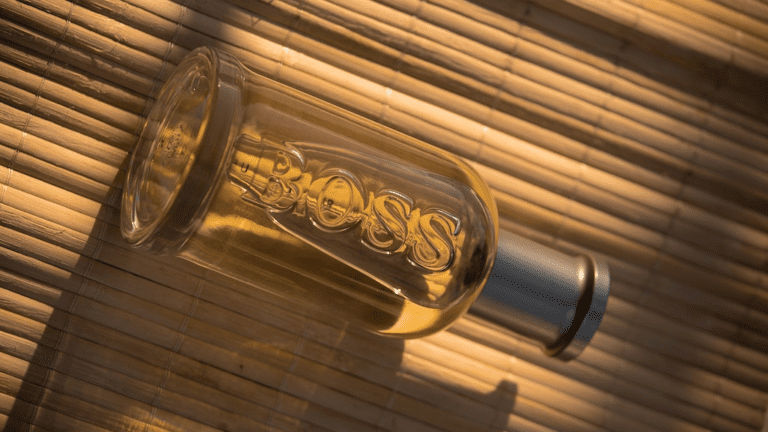 Frasco de perfume Boss de vidro transparente em superfície de madeira marrom
