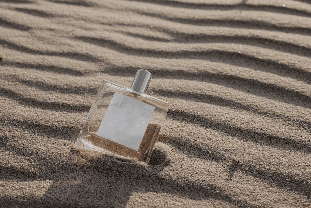 Close-up de frasco de perfume na areia com elemento de fixação.