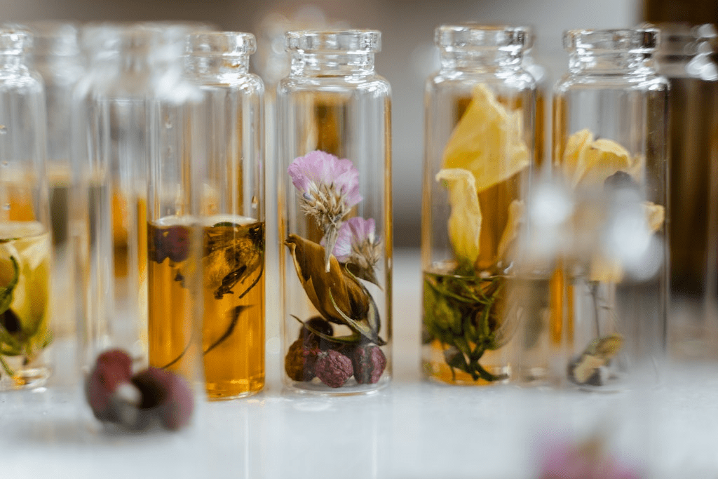 Frascos de vidro com líquidos e flores secas simbolizando notas olfativas.