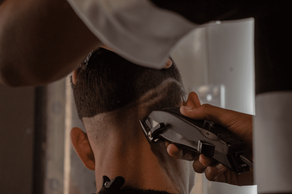 Homem cortando a barba com barbeador elétrico.